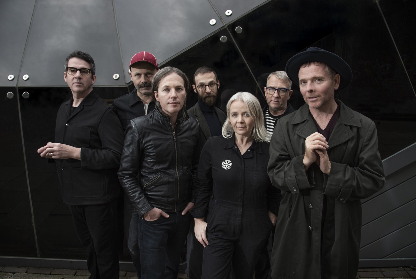 Group of the seven members of Belle & Sebastian. One female and the rest male, all dressed in dark clothing
